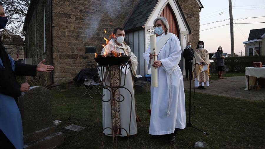 The Rev. Noah Evans helps Deacon Jean Chess light the Paschal candle during St. Paul’s Episcopal Church’s Easter sunrise service in Carnegie, Pa., on April 4, 2021. For many congregants, this was the first in-person worship service they had attended since a coronavirus surge in November 2020. Photo: Associated Press.