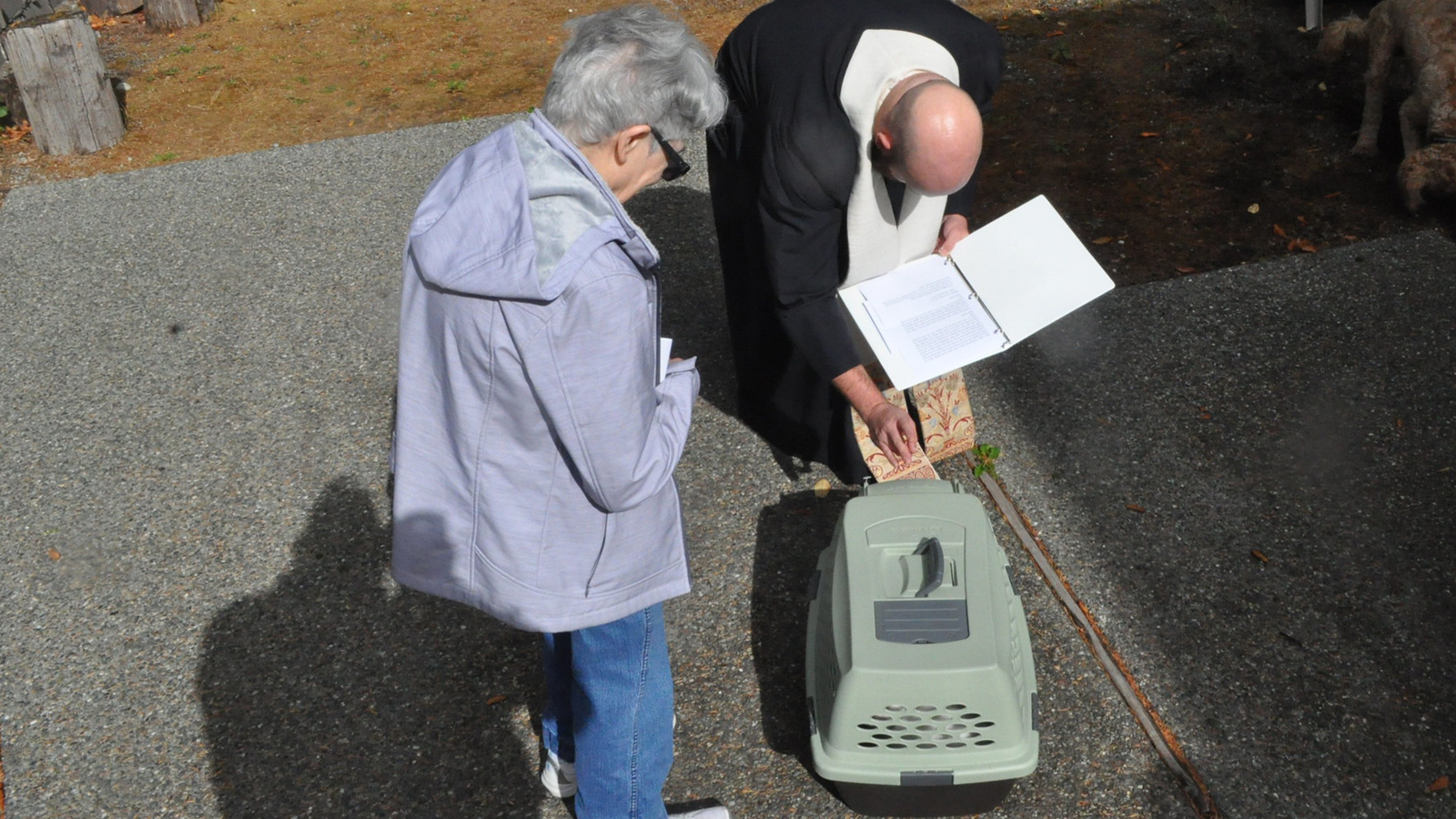 Father Jed blessing a cat in a carrier at the Redeemer campus.
