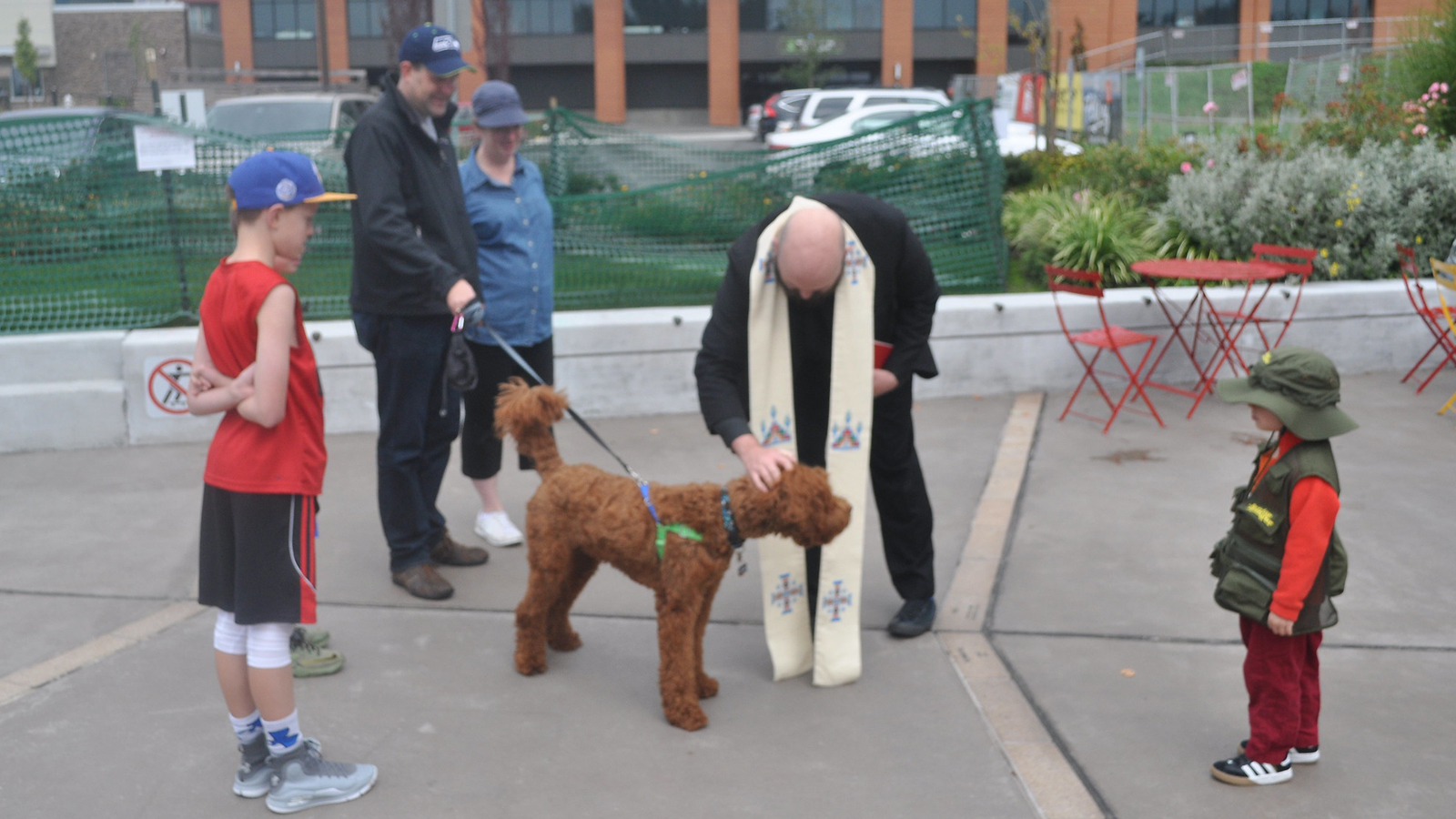 Father Jed blessing a family pet at Kenmore Town Square.