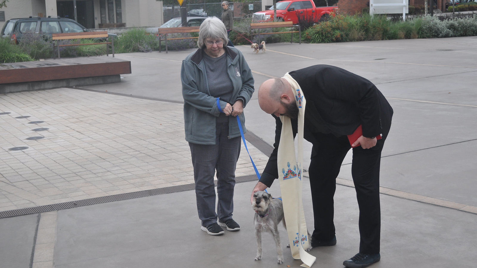 Father Jed blessing a dog at Kenmore Town Square.